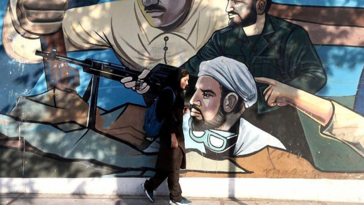 A woman walks past a mural depicting Iranian war heroes in downtown Tehran.