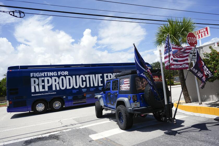 Supporters of Republican presidential nominee former President Donald Trump, who turned out to protest against abortion wait to follow the bus at the start of the "Reproductive Freedom Bus Tour" by the campaign of Democratic presidential nominee Vice President Kamala Harris and running mate Gov. Tim Walz, Tuesday, Sept. 3, 2024, in Boynton Beach, Fla. (AP Photo/Rebecca Blackwell)