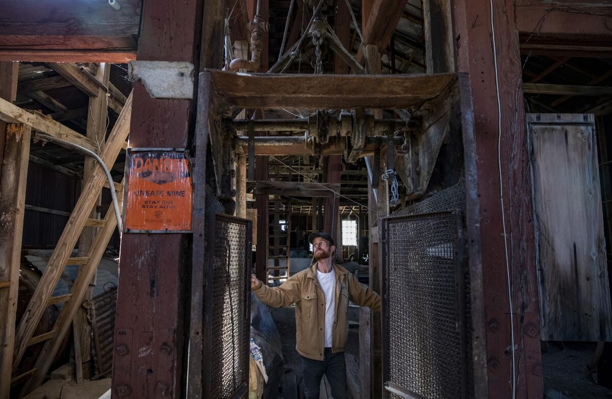 Brett Underwood stands between massive wooden posts of the headframe of the Union Mine in Cerro Gordo ghost town.
