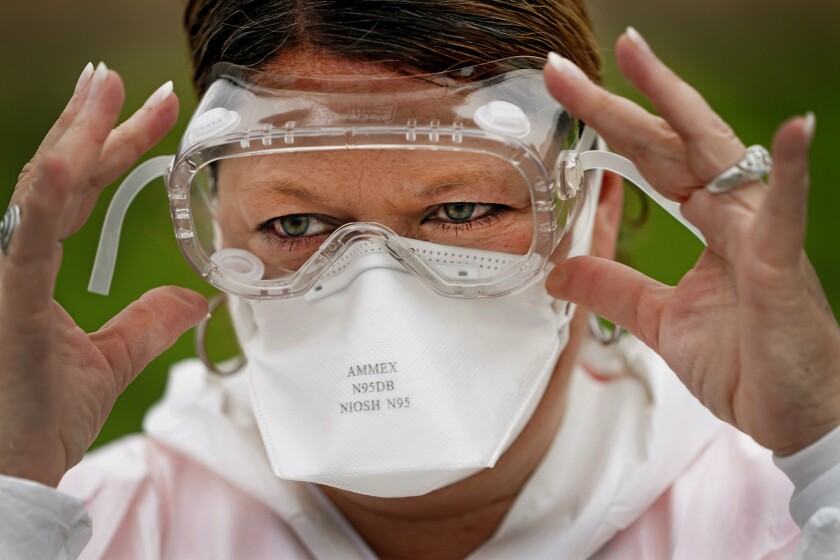 A nurse at a COVID-19 testing site adjusts her goggles