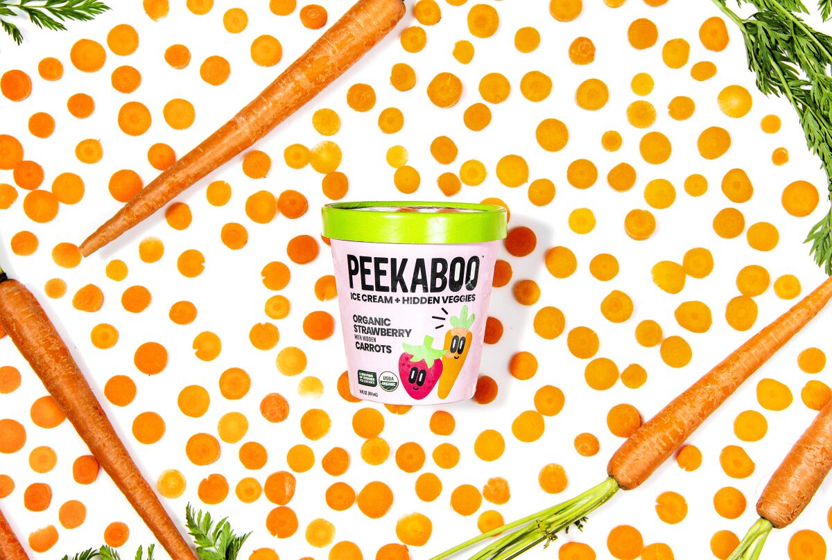  A carton of Peekaboo Ice Cream surrounded by sliced and whole carrots 