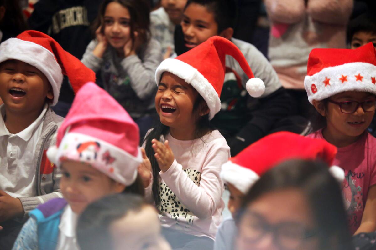 Students at Cerritos Elementary School react after hearing that every student at Cerritos will receive a holiday gift during a giveaway sponsored by Dignity Health Glendale Memorial Hospital in the school's auditorium on Monday.