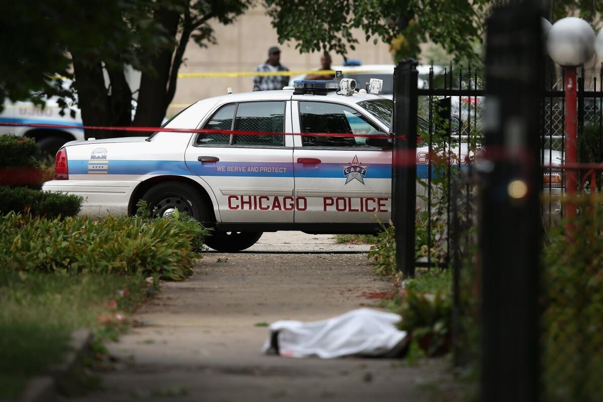 The body of a 14-year-old who was fatally shot in Chicago lies covered by a sheet as police investigate a rash of shootings across the city.