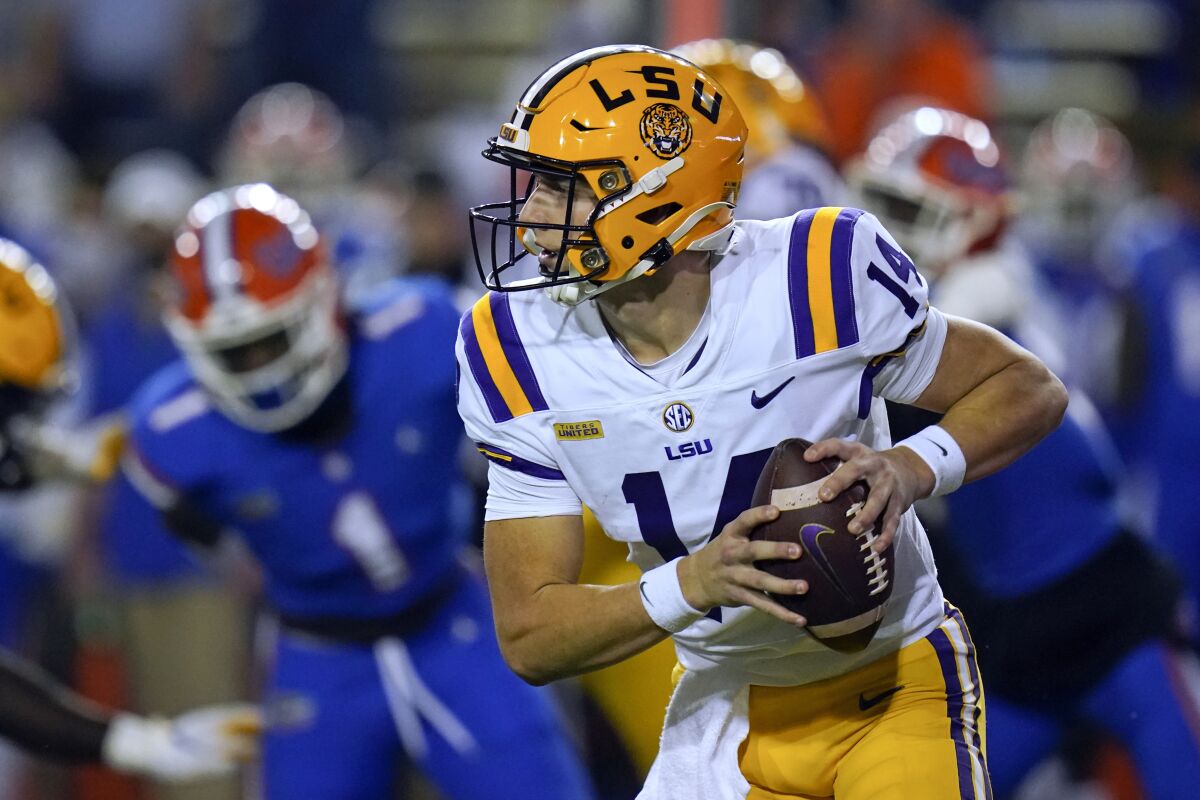 FILE - In this Dec. 12, 2020, file photo, LSU quarterback Max Johnson (14) scrambles during the first half of the team's NCAA college football game against Florida in Gainesville, Fla. While there are benefits to knowing now that Johnson will be LSU's starting quarterback, the Tigers also could profit from what looked to be a close competition for the position before Myles Brennan's fluke, off-the-field injury, coach Ed Orgeron said. (AP Photo/John Raoux, File)