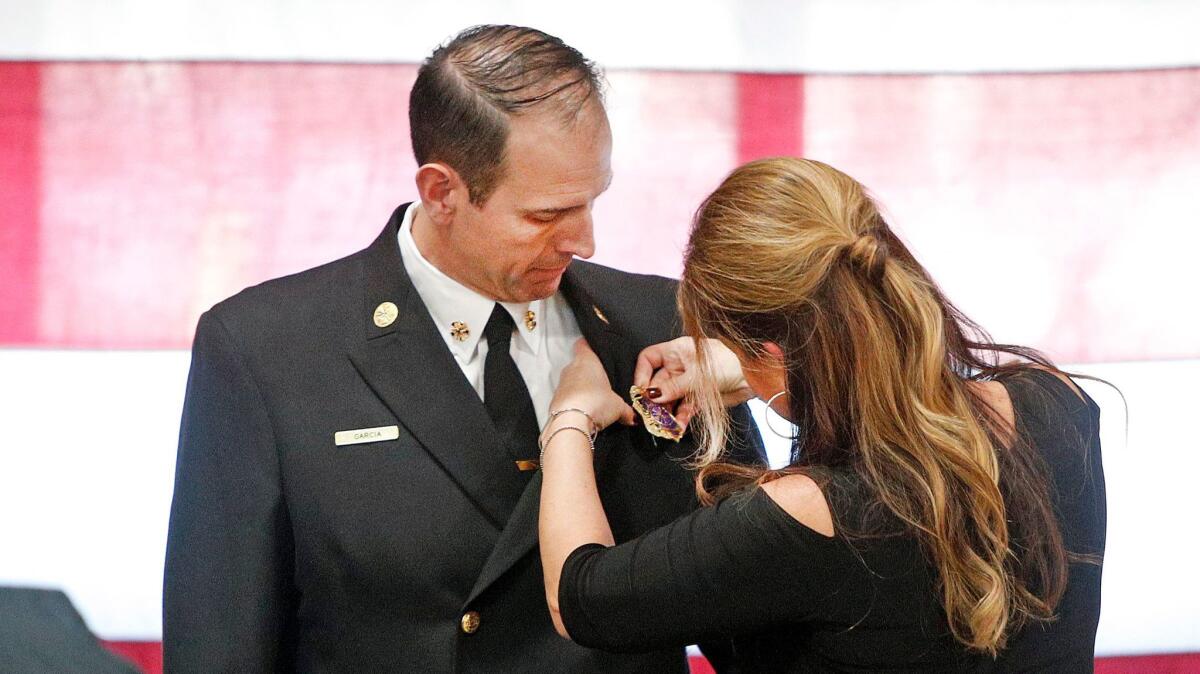 New Burbank Fire Chief Eric Garcia watches as his wife Cathy pins the chief's badge during the change-of-command ceremony at the department.