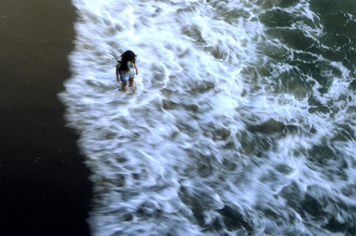 A beachgoer wades in the surf below the Santa Monica Pier on June 12.