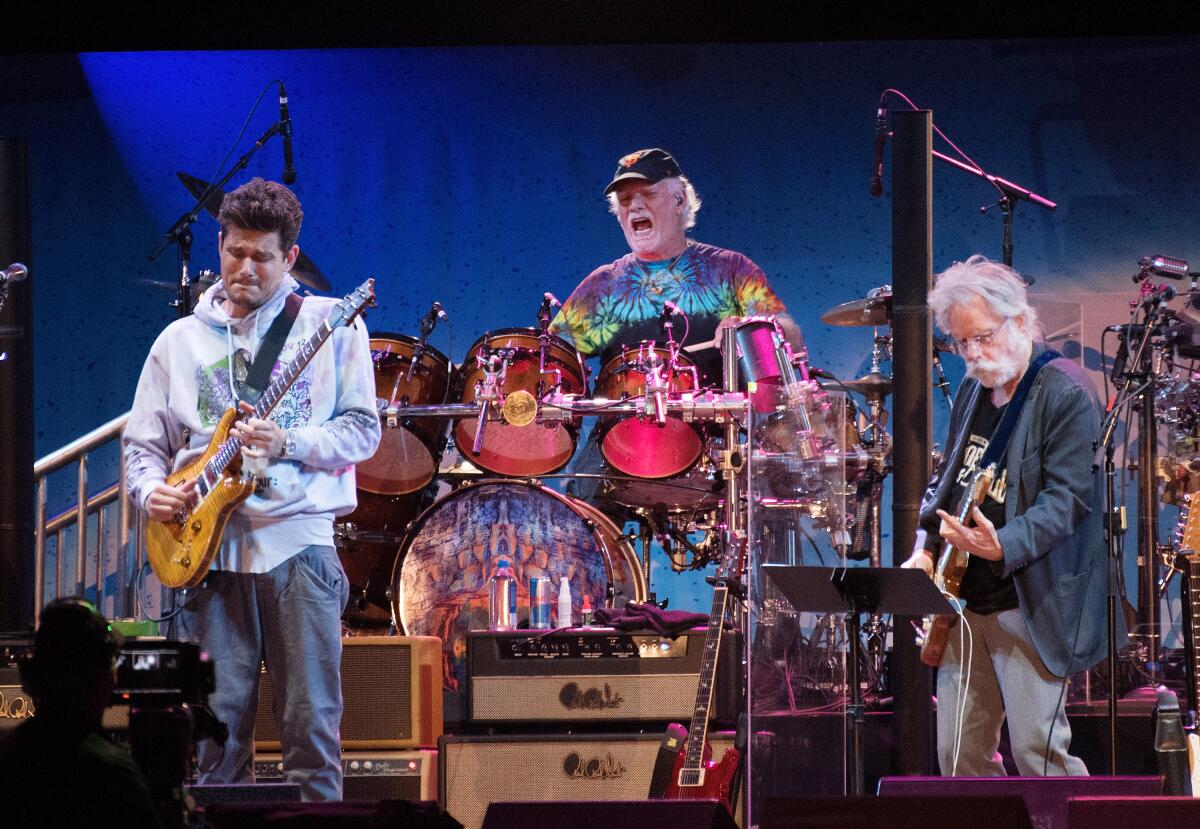  John Mayer on guitar, Bill Kreutzmann on drums and Bob Weir on guitar playing on a stage
