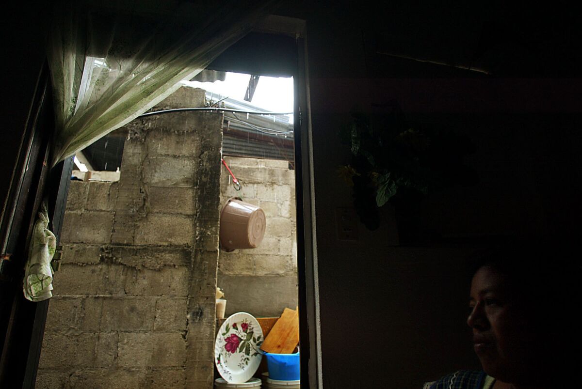Engracia Cirin sits inside a Guatemala City slum dwelling where she lives with her husband Antonio Paz. (Luis Sinco / Los Angeles Times)