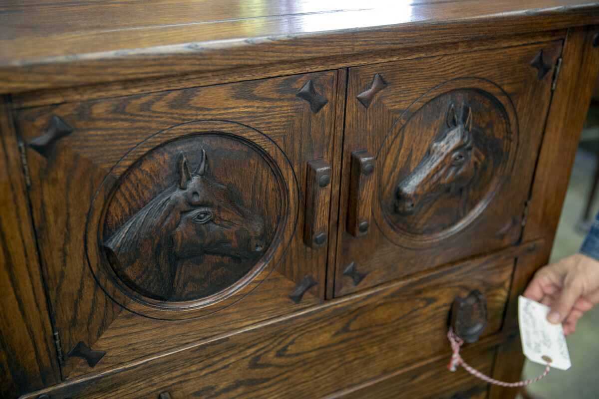 Nathan Turner checks the price on a chest of drawers with carved horse heads.