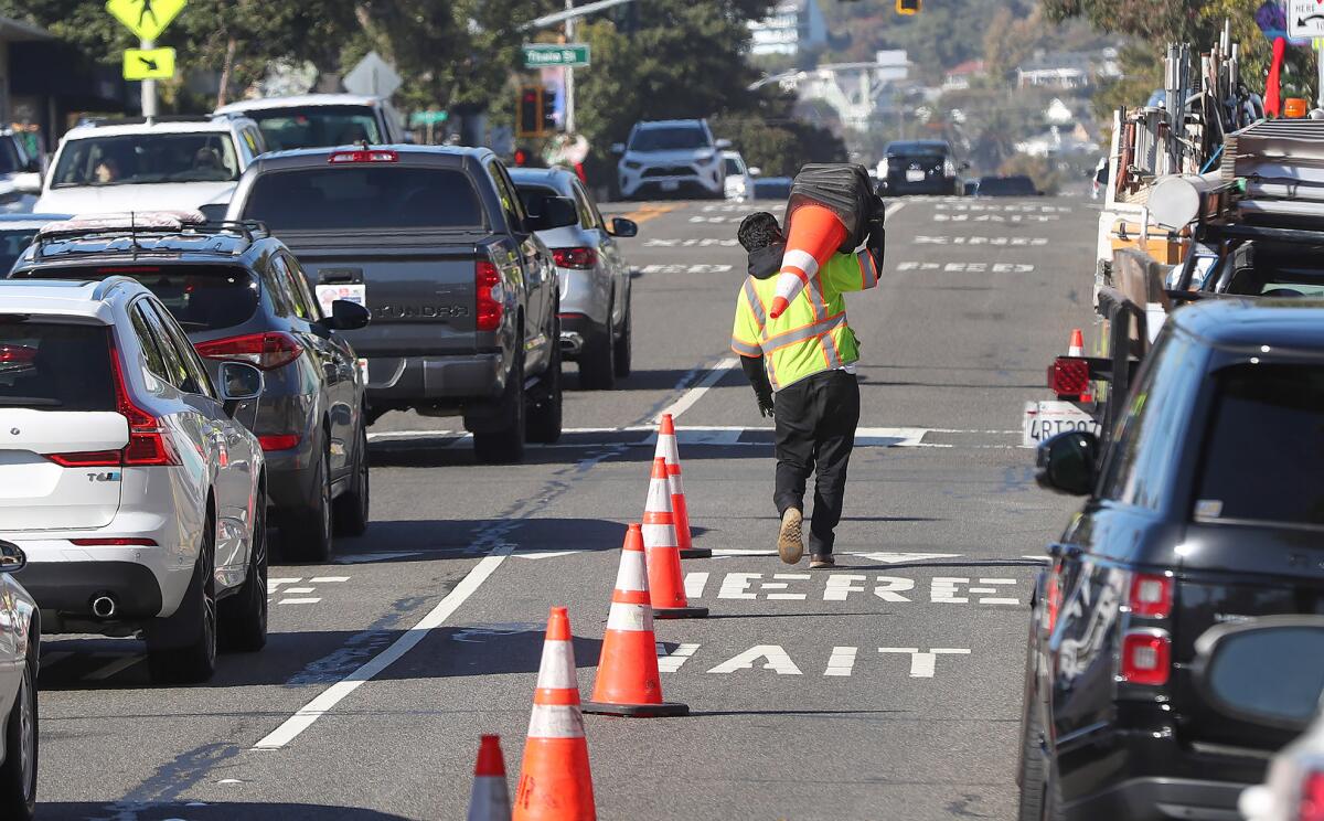 A Caltrans worker reduces traffic to one lane on Coast Highway at Oak Street as crews begin a project in Laguna Beach.