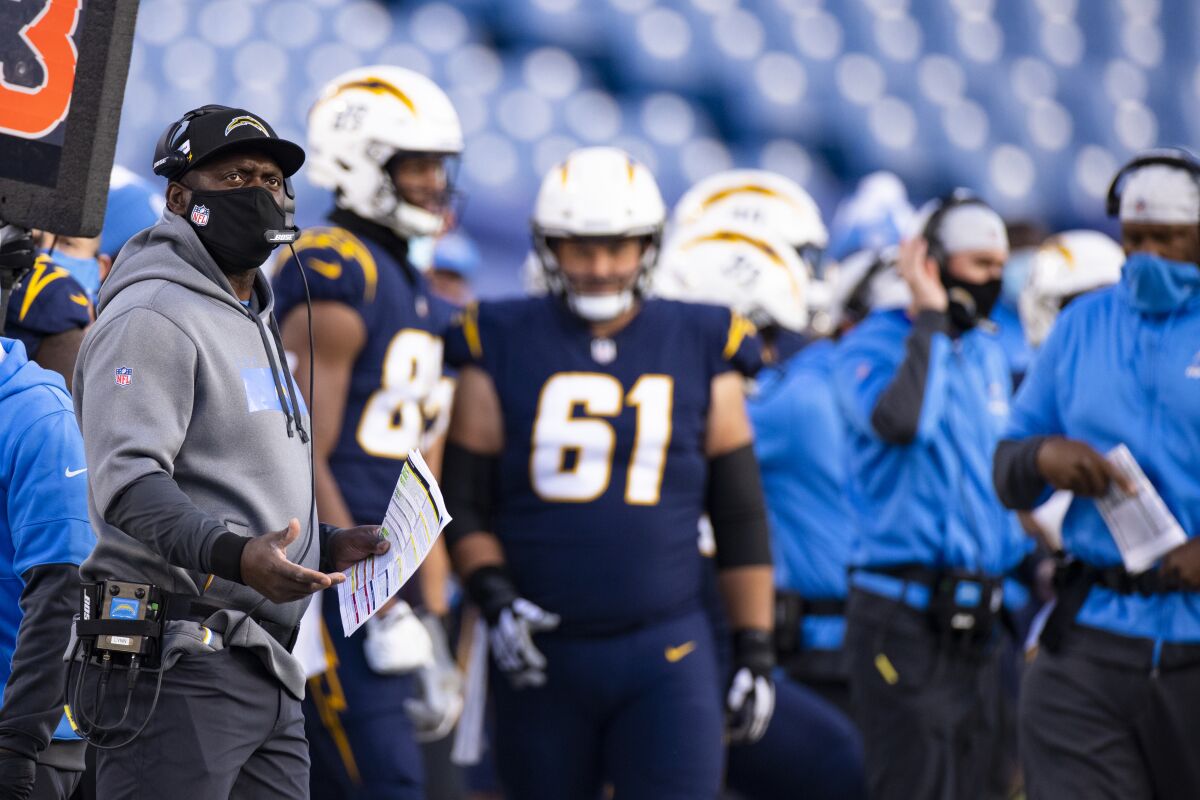Chargers head coach Anthony Lynn reacts on the sideline during the second half while players and staff stand nearby.