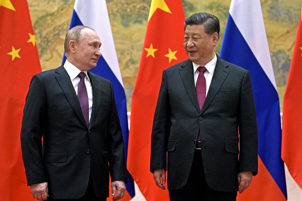 Chinese President Xi Jinping stands next to Russian President Vladimir Putin 