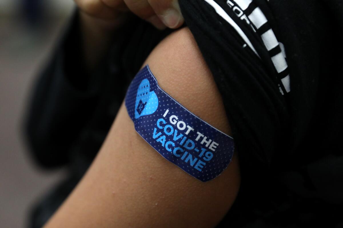 Adultos y niños se vacunan contra el COVID-19 en Delano, California.