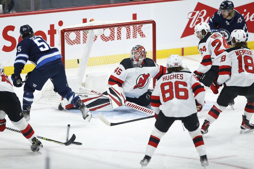 Winnipeg Jets' Mark Scheifele (55) scores on New Jersey Devils goaltender Jonathan Bernier (45) during the first period of an NHL hockey game Friday, Dec. 3, 2021, in Winnipeg, Manitoba. (John Woods/The Canadian Press via AP)