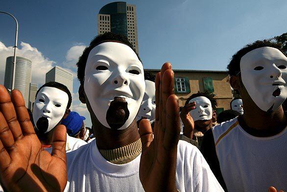Eritrean refugees, wearing white masks, participate in a protest in front of Israel's Defense Ministry in Tel Aviv. The protesters are seeking refugee status in Israel after coming in from a county where the U.N. says men are often forced into military service for life. Israel has granted refugee status to people fleeing Darfur, but says it will deport all others who have entered illegally.