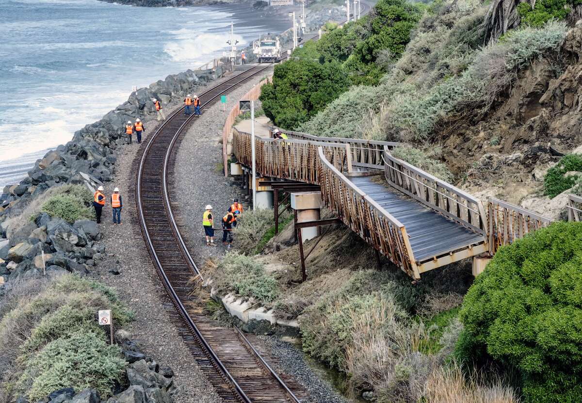 Workers investigate a landslide last week in San Clemente that damaged the pedestrian beach trail and stopped rail service