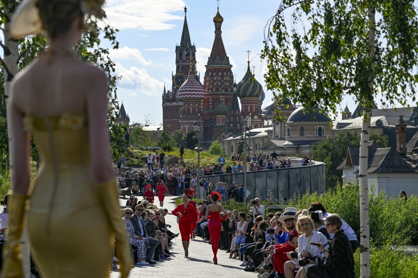 A model displays the collection by Russian designer Slava Zaitsev during the opening of the Fashion Week in at Zaryadye Park with the Spasskaya Tower and St. Basil's Cathedral in the background near Red Square in Moscow, Russia, Monday, June 20, 2022. Chic and adventurous models and couturiers have been spread all over the Russian capital for Moscow Fashion Week, flaunting their designs in venues ranging from a sprawling Stalin-era propaganda exposition to a large park near the Kremlin admired for its innovative features. More than 100 shows are being held during the week that began Monday as well as scores of speakers who are noted names in the Russian fashion industry. (AP Photo)