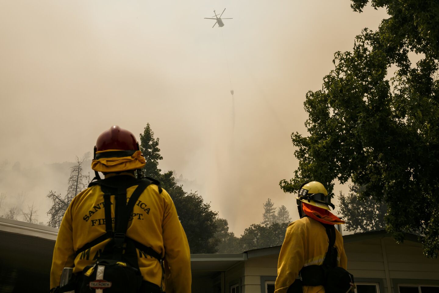 Helicopters attack the flames in the hills behind the Idle Wheels Senior Mobile Home in Mariposa, Calif.