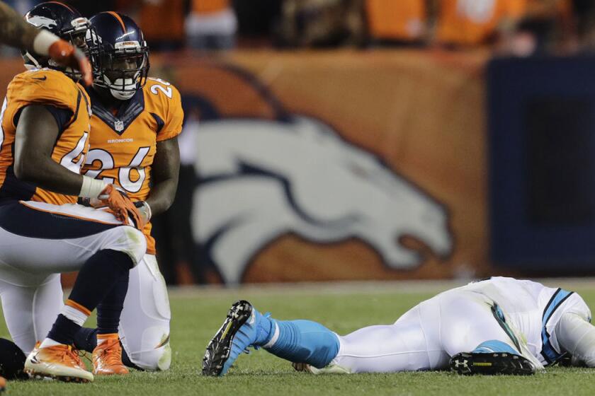 Carolina's Cam Newton lies on the turf after a hit to the head by Denver's Darian Stewart (26).