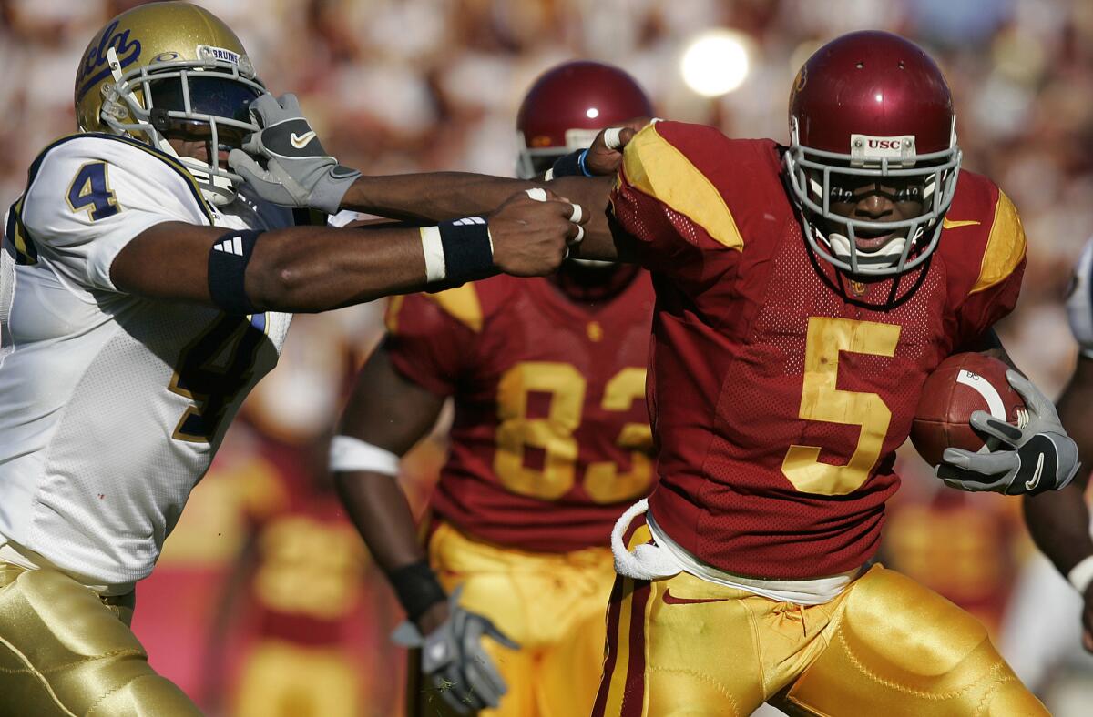USC's Reggie Bush stiff arms UCLA's Jarrad Page during a game in 2005.