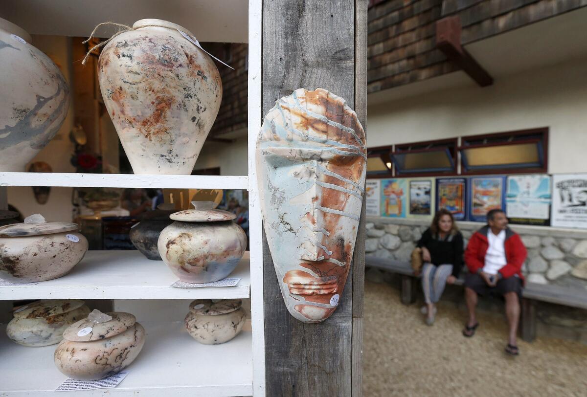 A ceramic mask made by artist Robert Jones hangs on his booth during the Sawdust Art Festival's locals preview night.