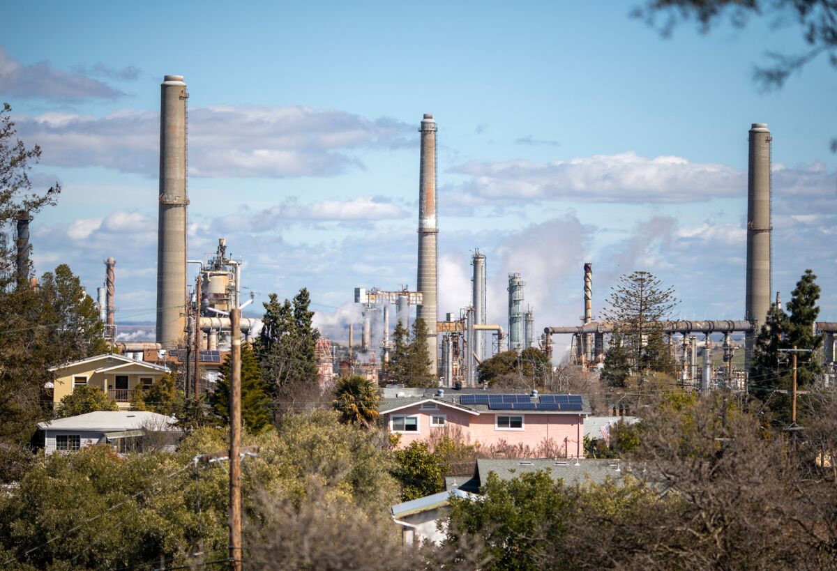 Industrial smokestacks rise behind a residential neighborhood.