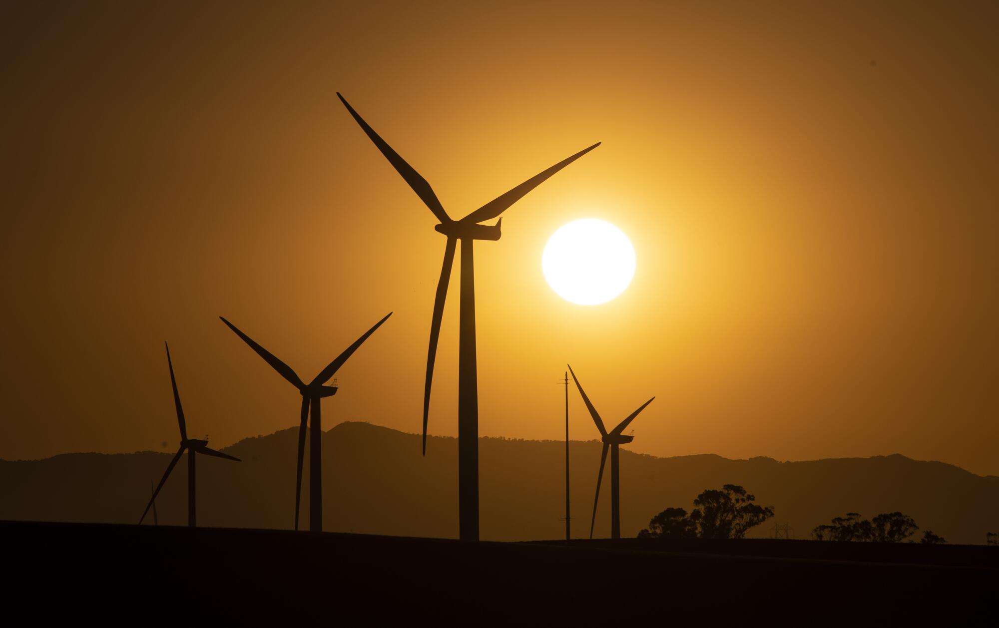 The sun sets among wind turbines.