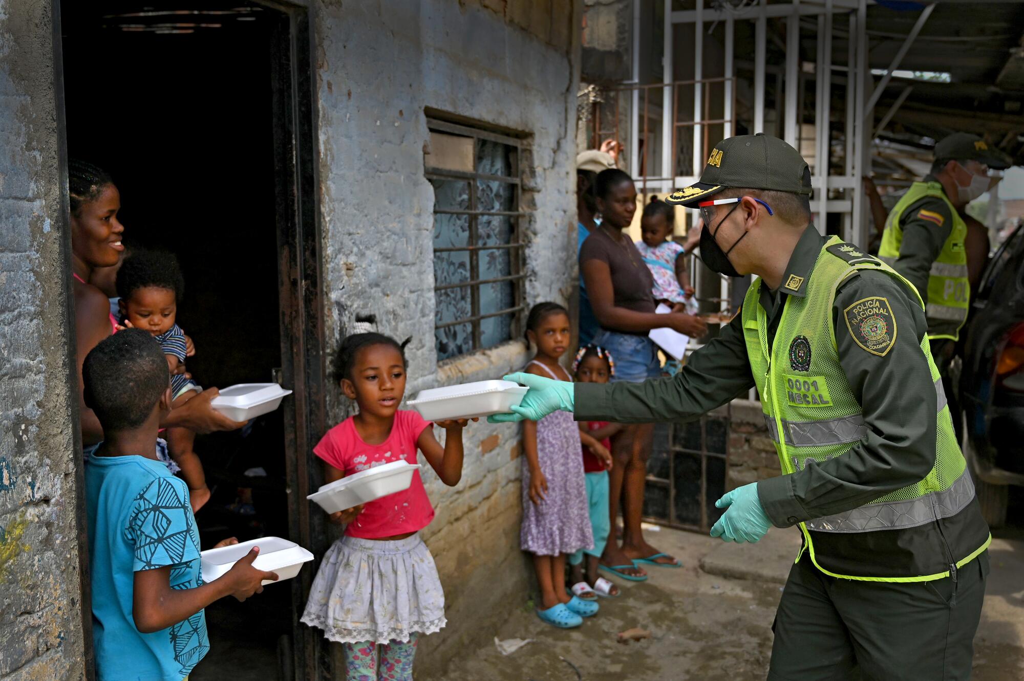 El jefe de policía Manuel Vásquez, a la derecha, entrega almuerzos a una familia, el 6 de mayo pasado en el distrito de Aguablanca de Cali, Colombia.