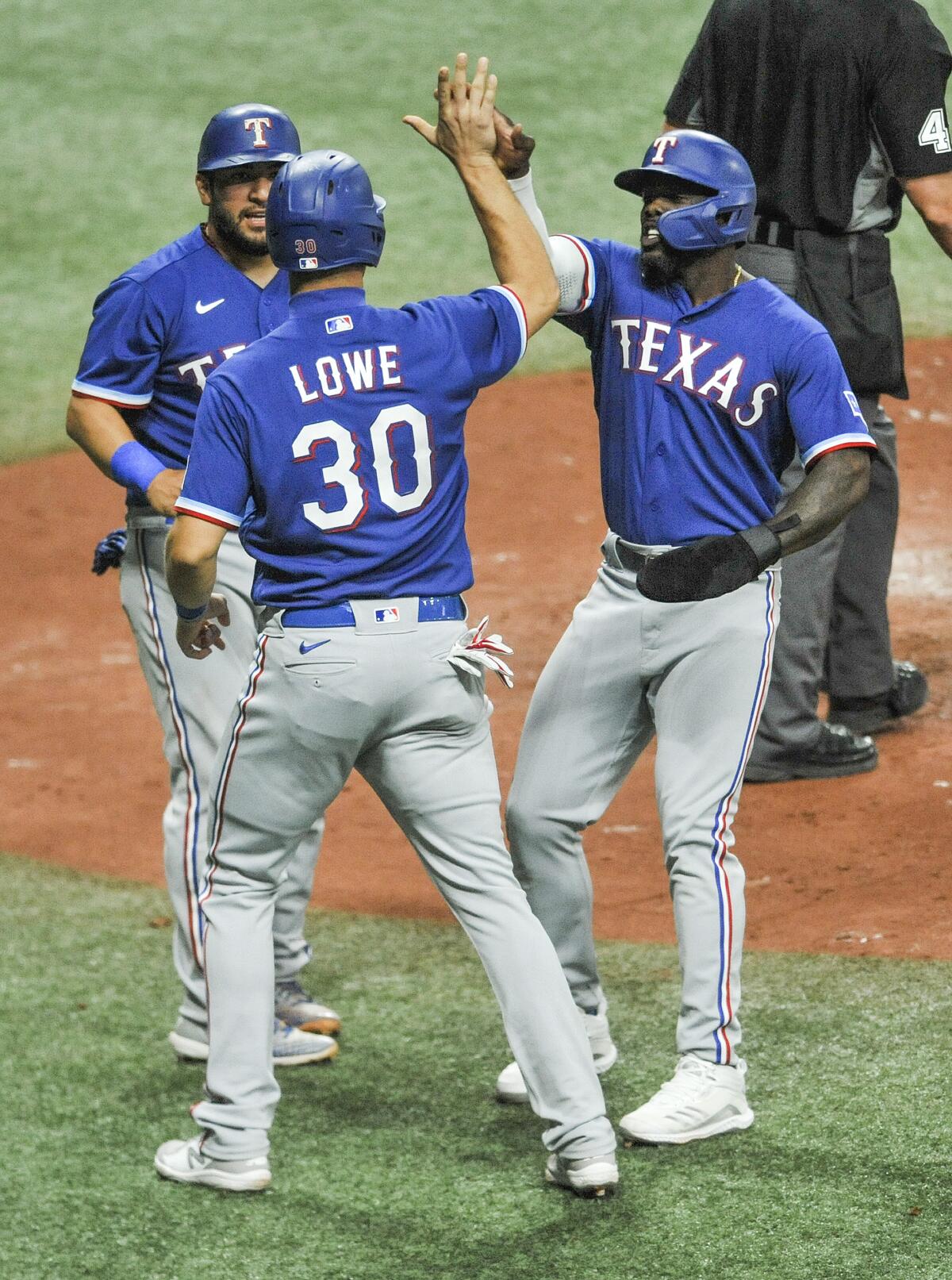 Texas Rangers' Jose Trevino, left, Nate Lowe (30) and Adolis Garcia celebrate after scoring on Nick Solak's bases-loads double off Tampa Bay Rays' Ryan Yarbrough during the fourth inning of a baseball game Tuesday, April 13, 2021, in St. Petersburg, Fla. (AP Photo/Steve Nesius)