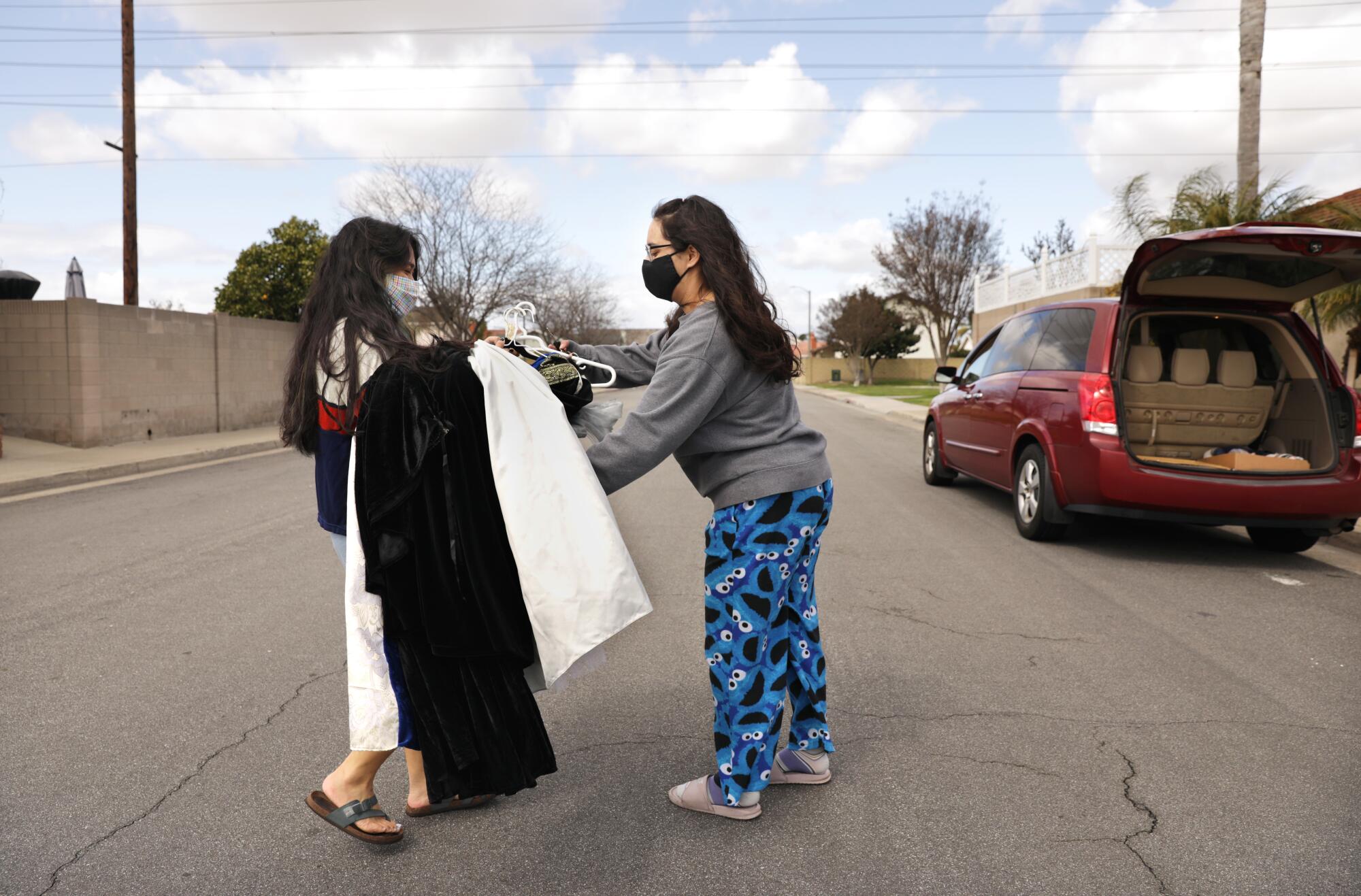 Maxime Garcia, right, takes costumes from her friend Jazlyn Cariaga for a virtual school play