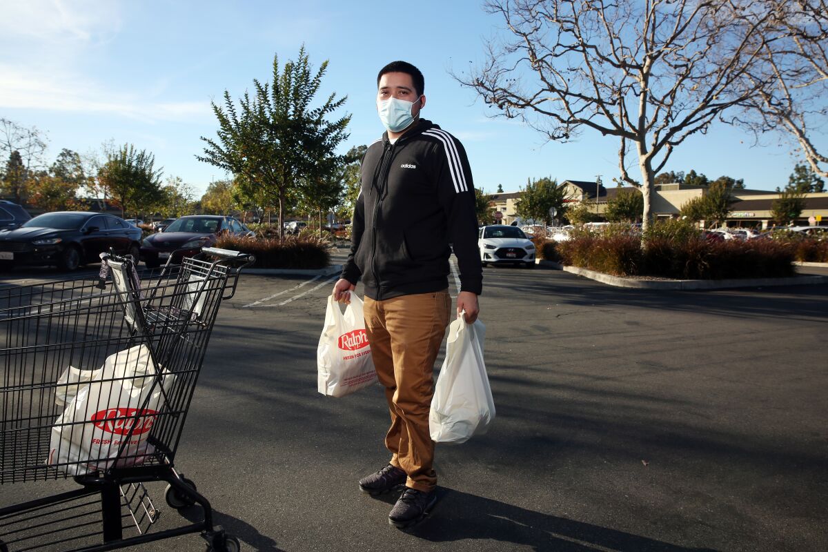 A man stands in a parking lot holding grocery bags