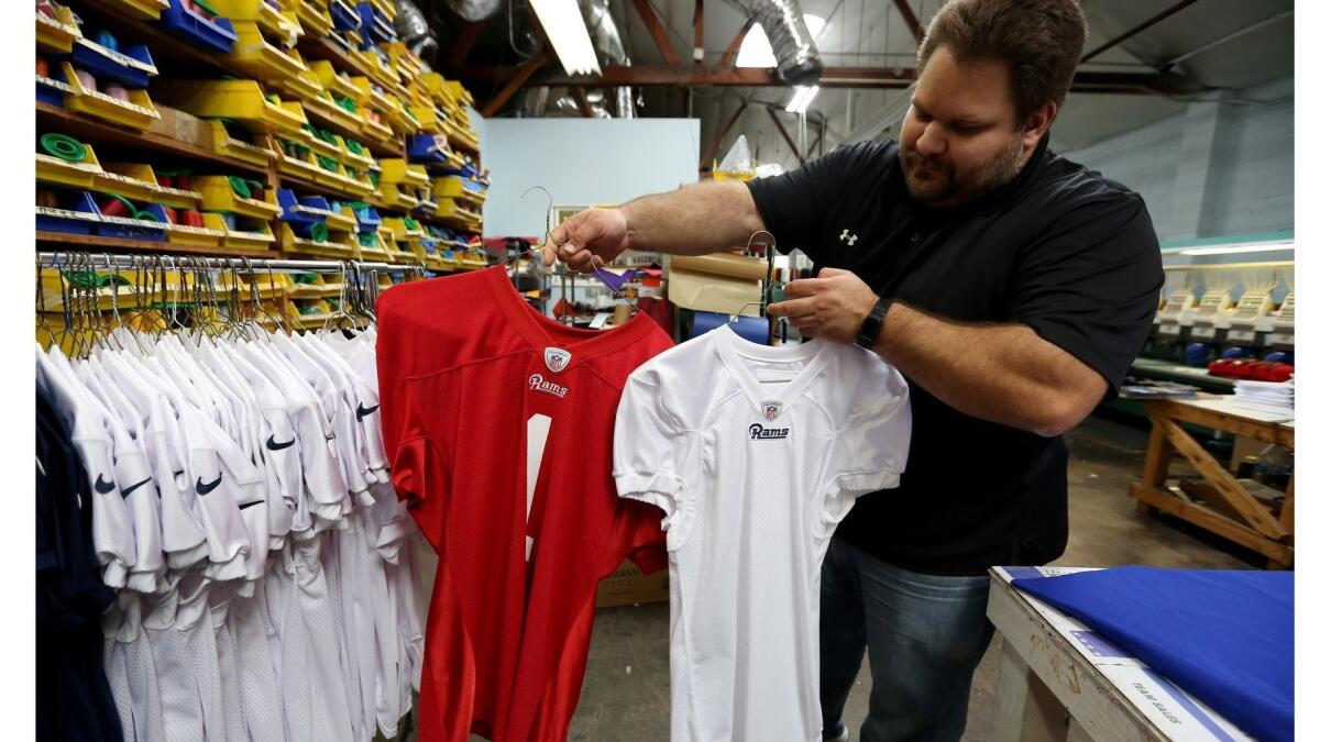 Buddy's All Stars marketing manager Scott Talamantes shows the Los Angeles Rams practice jerseys the company makes at their warehouse in Burbank.