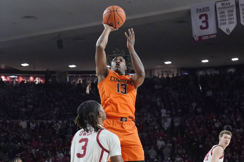 Oklahoma State guard Quion Williams (13) shoots over Oklahoma guard Otega Oweh (3) in the first half of an NCAA college basketball game Wednesday, Feb. 1, 2023, in Norman, Okla. (AP Photo/Sue Ogrocki)