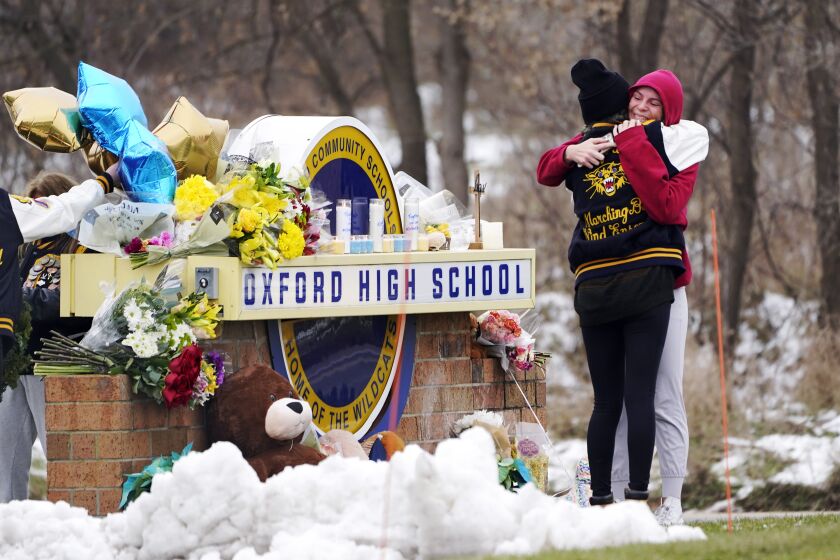 FILE — Students hug at a memorial at Oxford High School in Oxford, Mich., Dec. 1, 2021. School systems nationwide rely on high-level expertise from the U.S. Secret Service and others as they work to stay vigilant for signs of potential student violence, training staff, surveilling social media and urging others to tip them off. However, when it comes to deciding how to respond to a possible threat, it’s the local educators who make the call. (AP Photo/Paul Sancya, File)