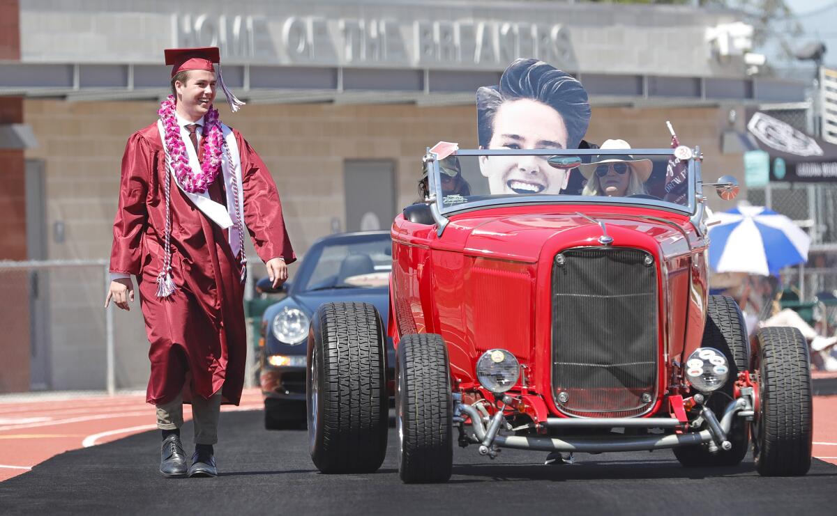 Graduate Andrew Fink, walks along side his grandpa's 1932 Ford hot rod at the Laguna Beach High drive-through graduation.