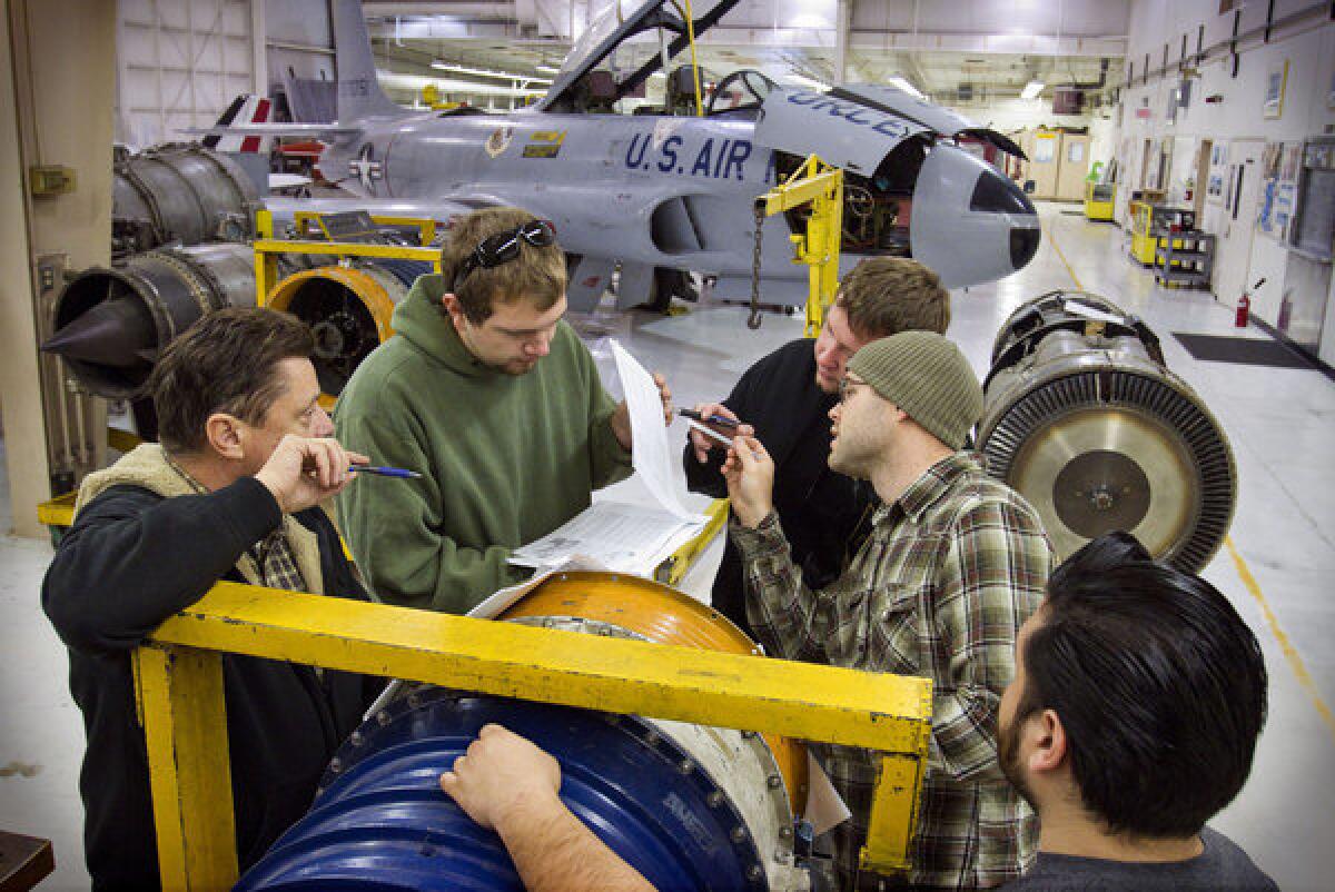 Instructor David Bowerman, at left, talks with students around a jet engine at the aviation mechanics school.