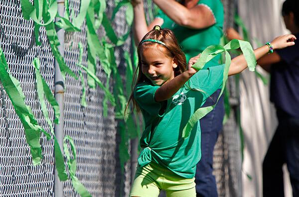 Second-grader Bella Blaylock, 7, runs with a green ribbon to tie to the Kelly Elementary School playground fence. Three days after an assailant wounded two second-grade girls on the playground, principal Tressie Armstrong invited parents and kids to a picnic to celebrate their good fortune that the gunman was stopped.