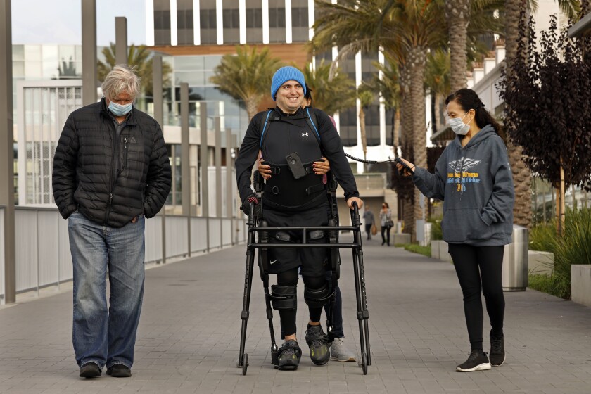 Ignacio Montoya uses an exoskeleton suit and robotic legs to help him walk along the boardwalk in Marina del Rey.