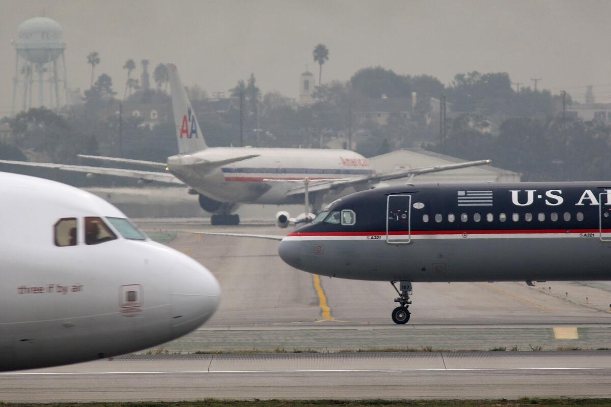 Jets of US Airways, American Airlines and other carriers taxi at Los Angeles International Airport.