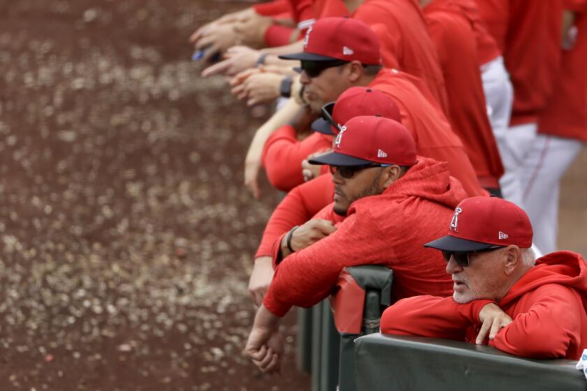 Los Angeles Angels manager Joe Maddon, front right, watches with his team from the dugout during the fourth inning of a spring training baseball game against the Texas Rangers Friday, Feb. 28, 2020, in Tempe, Ariz. (AP Photo/Charlie Riedel)