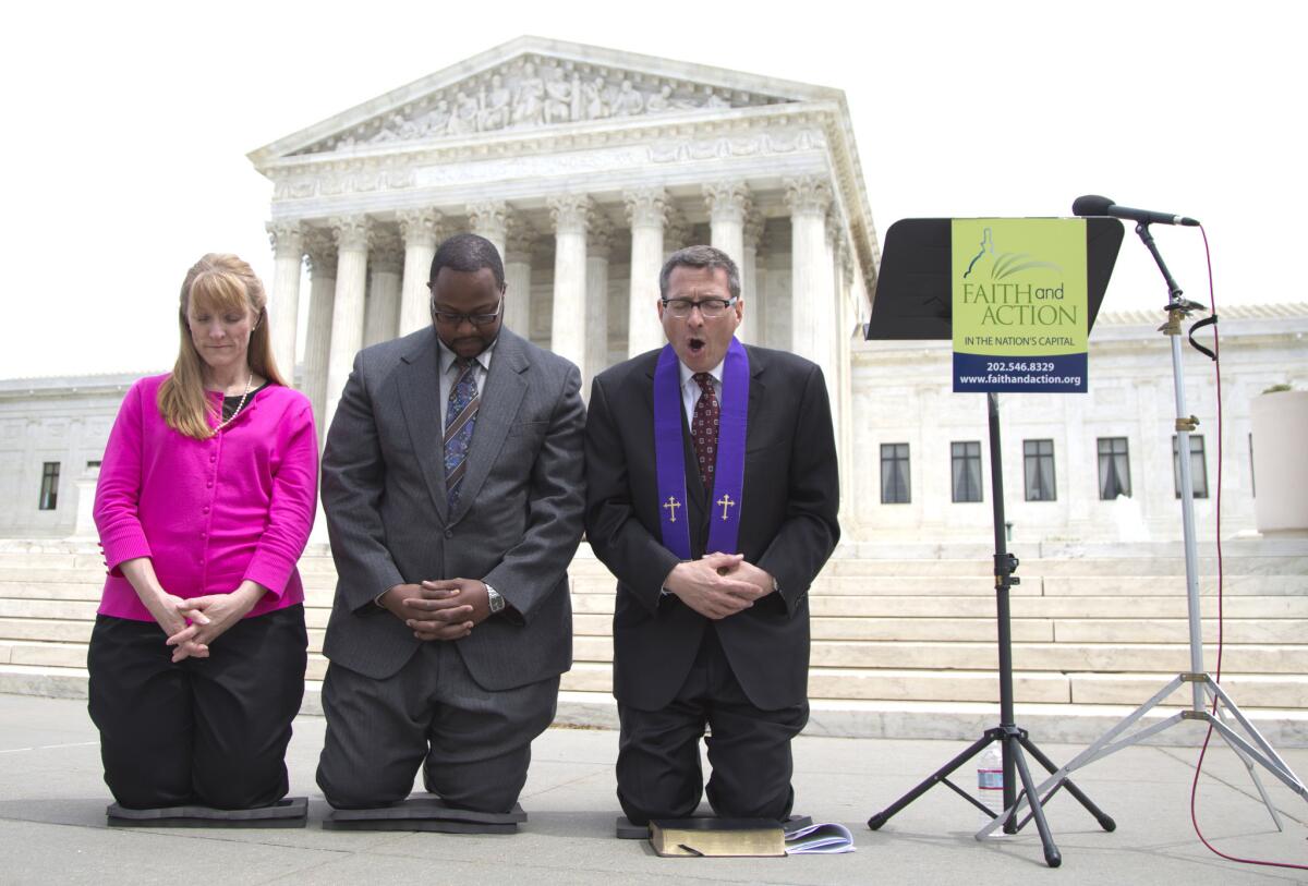 Rev. Dr. Rob Schenck, of Faith and Action, right, prays in front of the Supreme Court with Raymond Moore and Patty Bills during a news conference in Washington after speaking in favor of the Supreme Court's ruling upholding Christian prayers at the start of local council meetings.