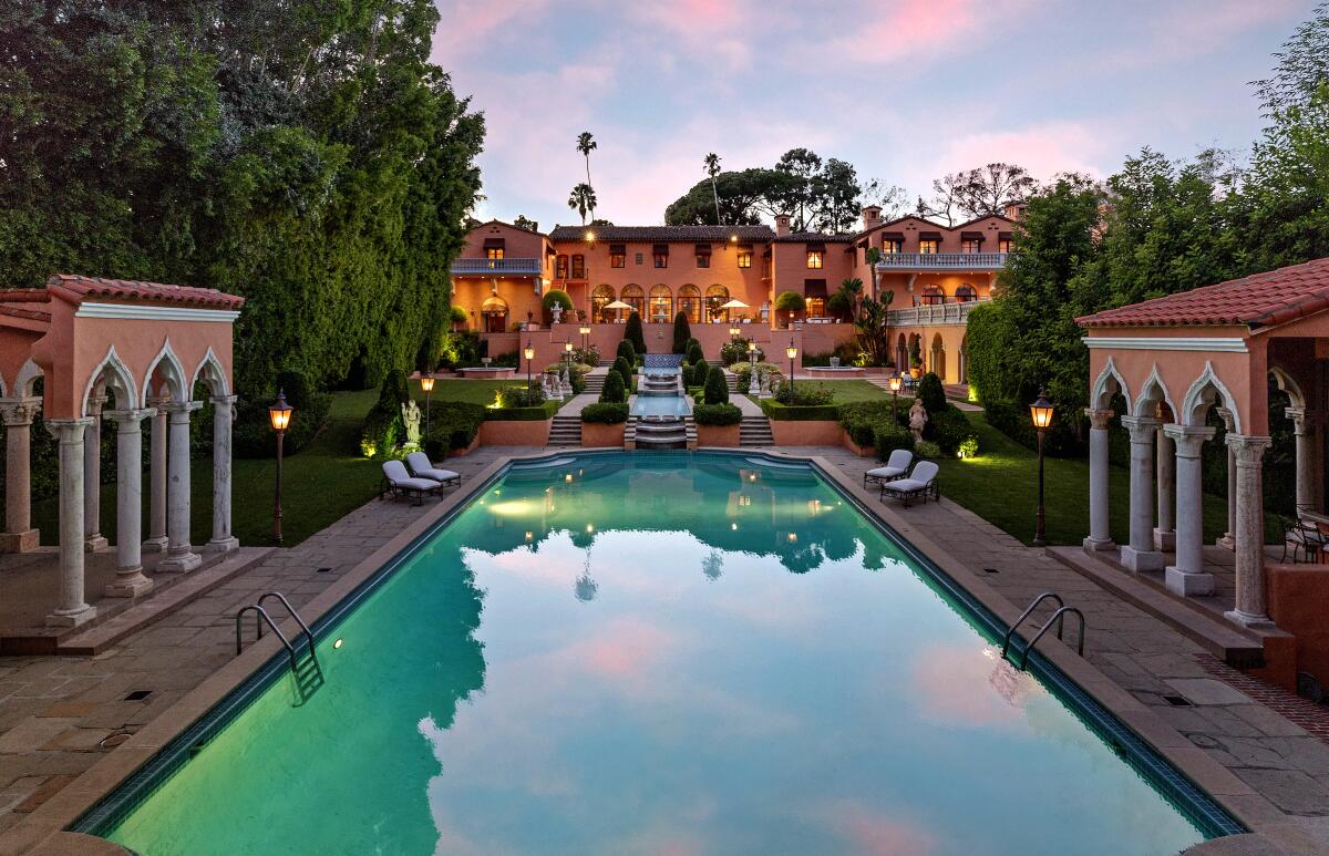 A long rectangular pool with a mansion in the background.