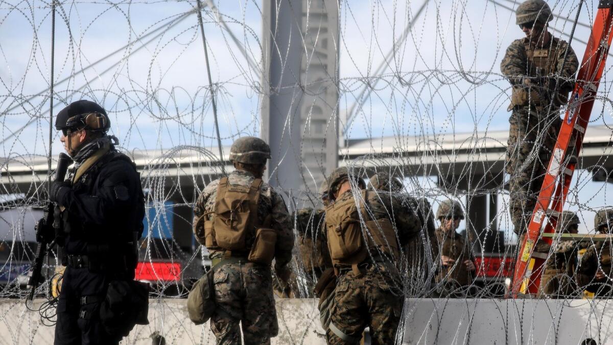 A U.S. Customs and Border Protection agent, left, stands watch on Thanksgiving Day as troops set up concertina wire at the San Ysidro border crossing into Tijuana, Mexico.