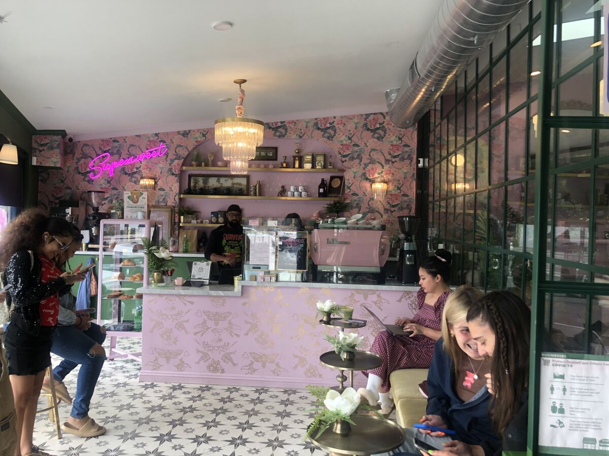 women sit at a pink coffee bar 