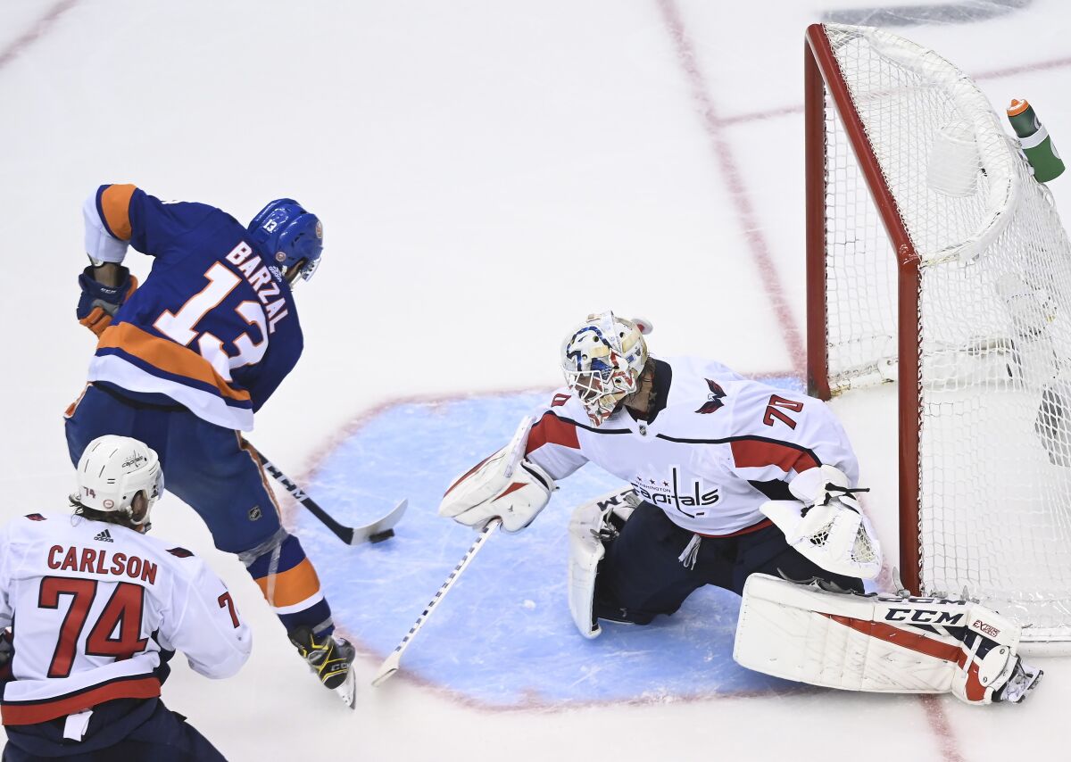 New York Islanders center Mathew Barzal (13) scores the winning goal past Washington Capitals goaltender Braden Holtby (70) as Capitals defenseman John Carlson (74) looks on during overtime NHL Eastern Conference Stanley Cup playoff hockey action in Toronto, Sunday, Aug. 16, 2020. (Nathan Denette/The Canadian Press via AP)