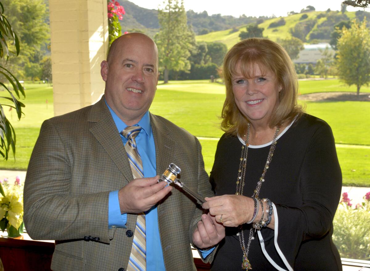 Outgoing chairman of the Burbank Chamber of Commerce Darin Chase passes the gavel to the organization's new chairwoman, Karen Volpei, during last week’s installation luncheon at Lakeside Golf Club.
