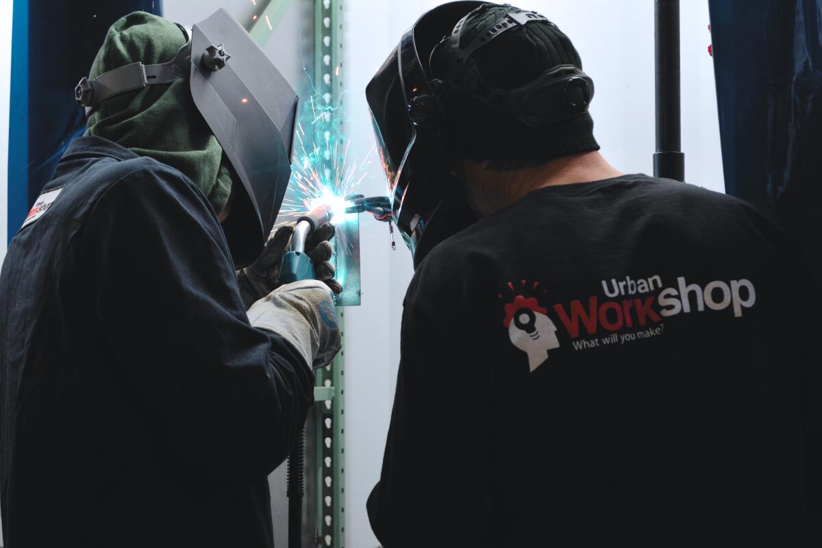 Welding instructor Chris Lynch, right, works with a student at the Urban Workshop in Costa Mesa.