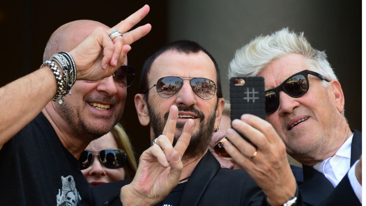 Ringo Starr takes a selfie while joined by fashion designer John Varvatos, left, wife Barbara Bach, rear, and filmmaker David Lynch, right, in Hollywood in 2014 on his 74th birthday.