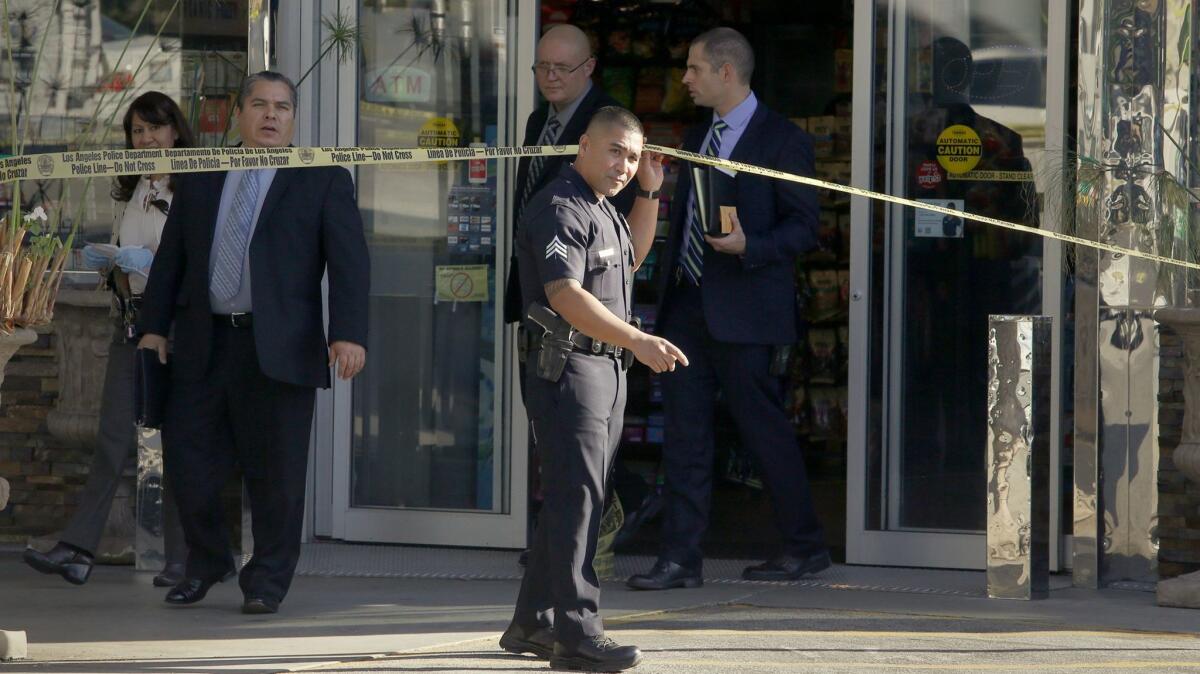 LAPD investigators emerge from a Chevron station mini mart where a store clerk was shot to death during a robbery in Los Feliz on Jan. 17.