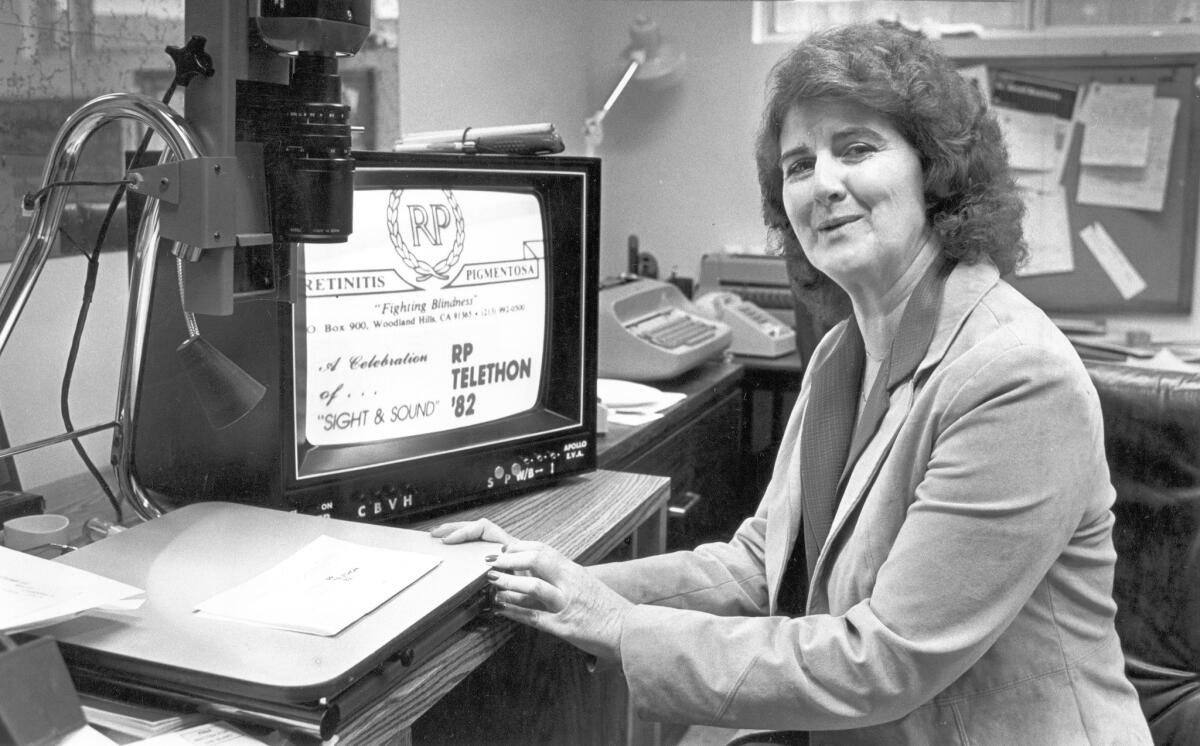Helen Harris in her office in her Woodland Hills home in 1982, using a TV camera and monitor to read letters. On the screen is the logo for Retinitis Pigmentosa Foundation Inc. Harris raised millions for eye research.